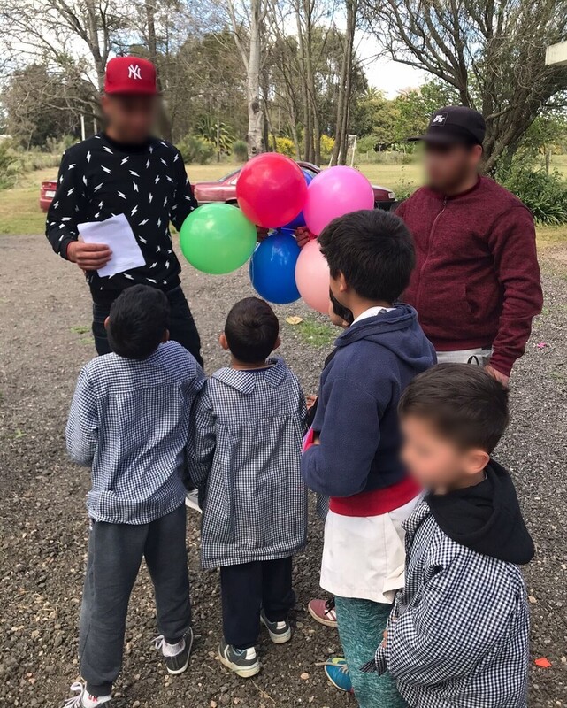 Jóvenes del centro entregando globos a los niños